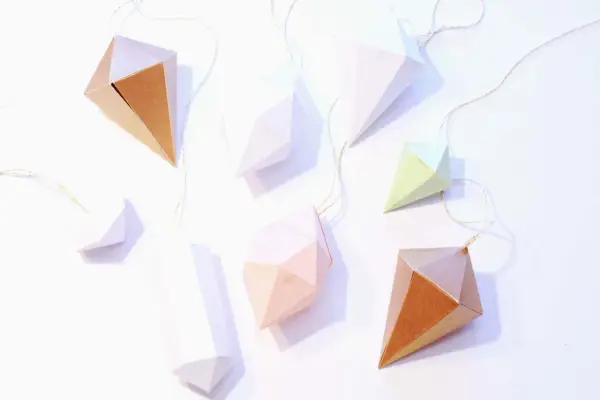 Papierdiamanten in verschiedenen Farben und Größen, die an goldenen Fäden hängen. Eine tolle Idee für eine diamant basteln vorlage.