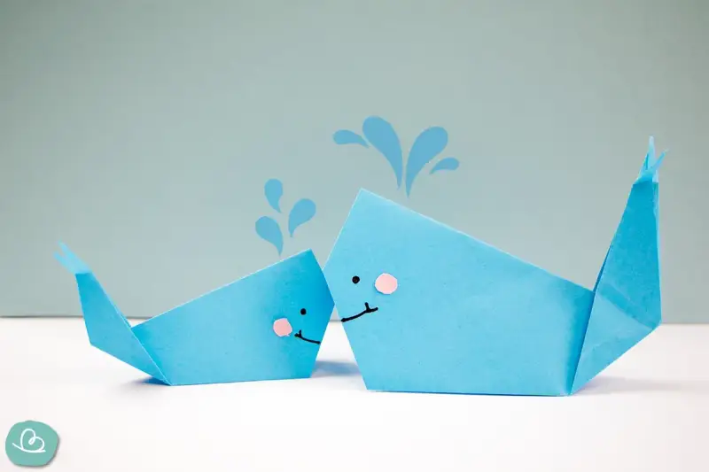 Zwei niedliche Origami-Wale, die Wasser spritzen.